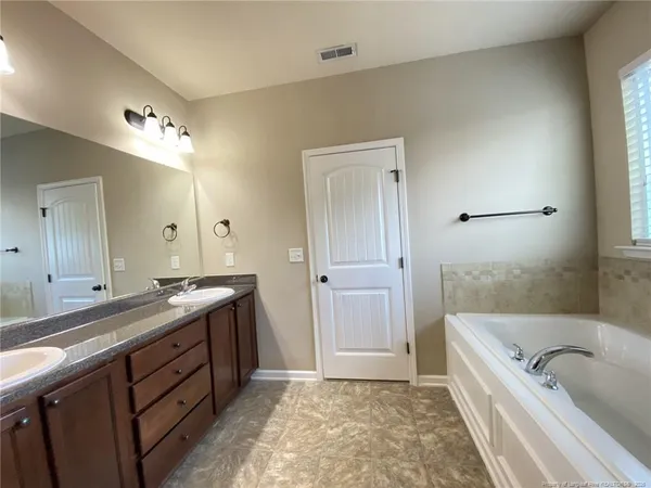 a spacious bathroom with a tub sink and mirror