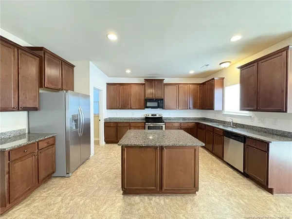 a kitchen with stainless steel appliances granite countertop a sink stove and refrigerator