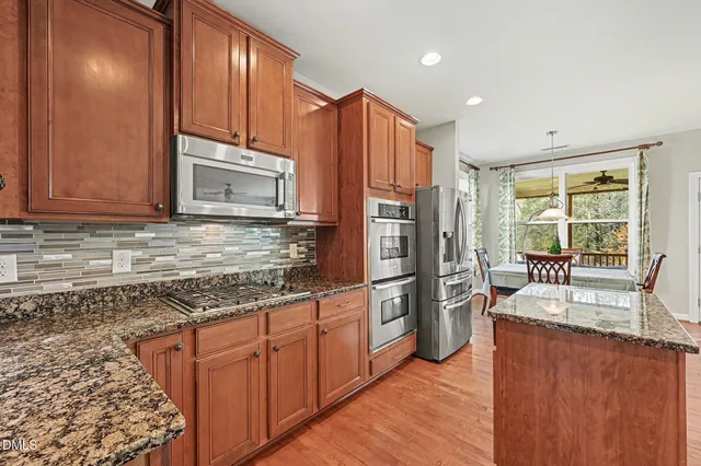 a kitchen with granite countertop kitchen island wooden cabinets and stainless steel appliances