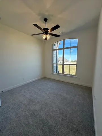 an empty room with windows and fan