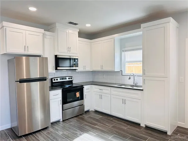 a kitchen with white cabinets and stainless steel appliances