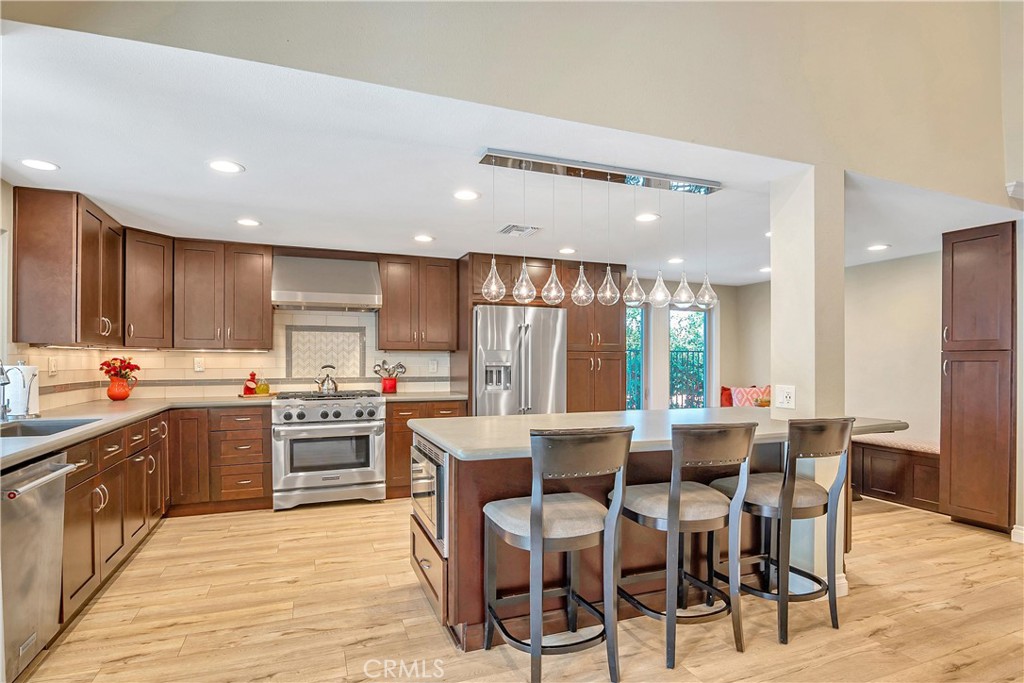 28604 Eagleton Street Agoura Hills, CA 91301 - Photo 18 of 72 a kitchen with stainless steel appliances kitchen island granite countertop a table chairs sink and cabinets