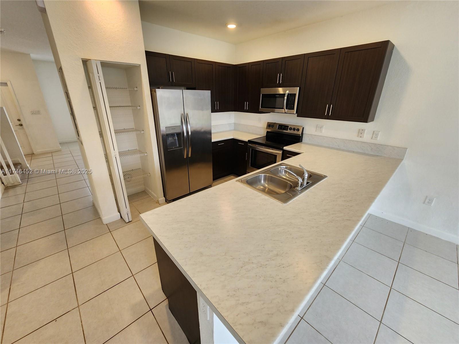 18232 Southwest 148th Road, Unit 18232 Miami, FL 33187 - Photo 13 of 44 a kitchen with stainless steel appliances granite countertop a refrigerator and a sink
