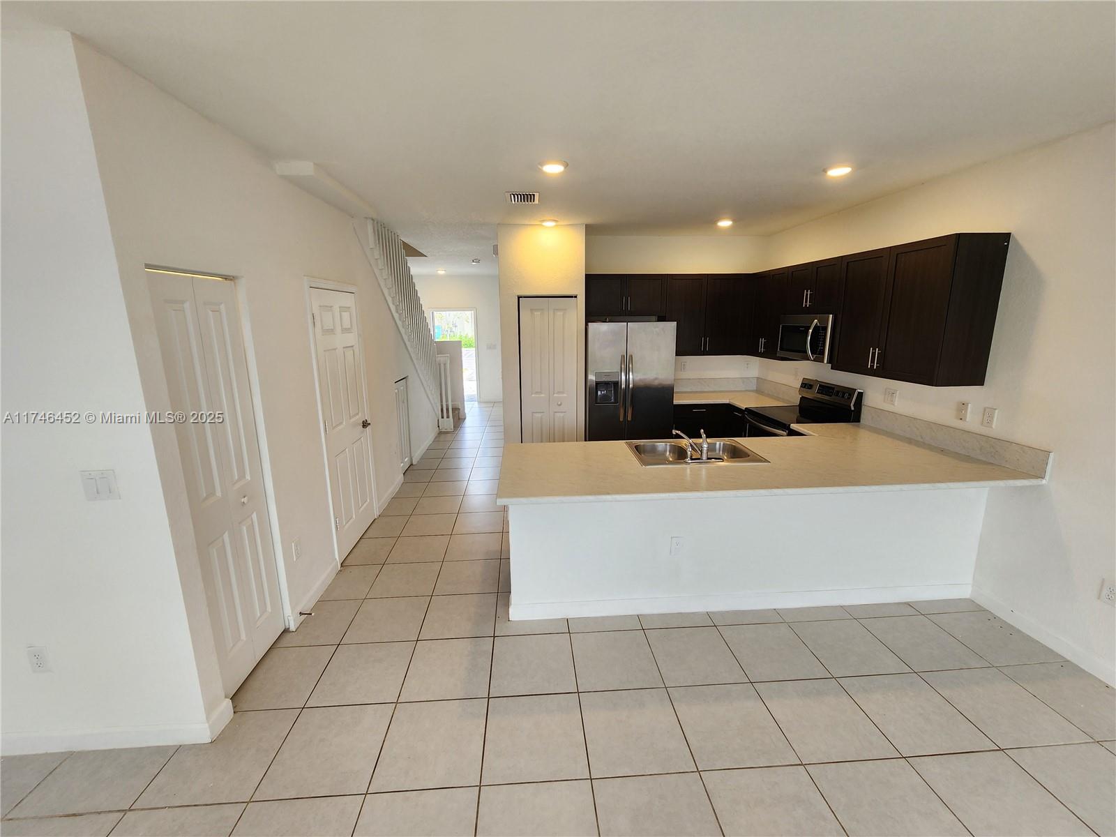 18232 Southwest 148th Road, Unit 18232 Miami, FL 33187 - Photo 9 of 44 a large white kitchen with a large mirror vanity and view of living room