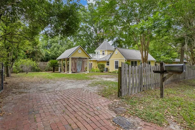 a view of a house with a yard and large trees