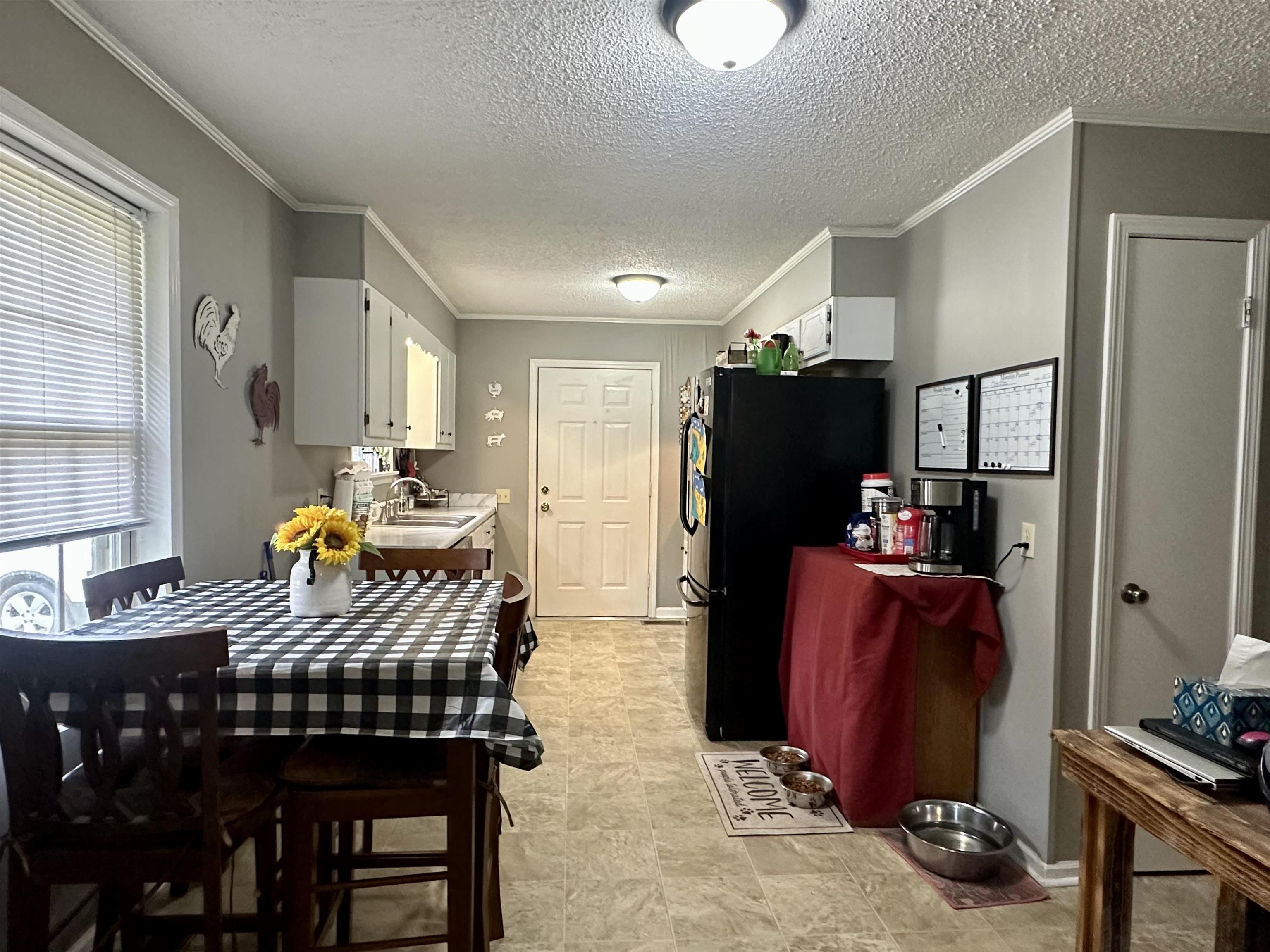 320 Clayton Road Finger, TN 38334 - Photo 7 of 16 Kitchen featuring white cabinets, light countertops, freestanding refrigerator, a textured ceiling, and crown molding
