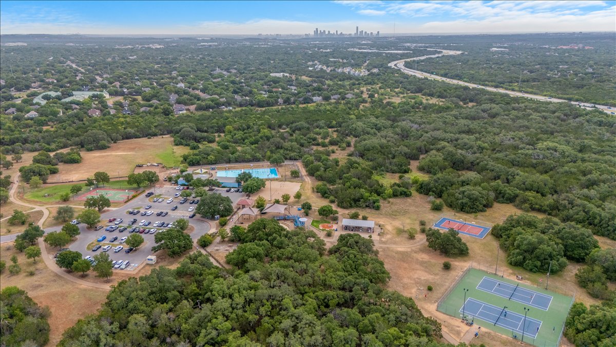 9012 Meacham Way Austin, TX 78749 - Photo 31 of 34 Expansive aerial view showcasing a dense tree canopy, multiple tennis courts, and a large parking area