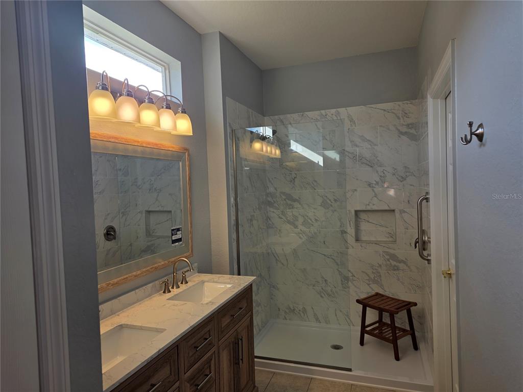 13185 Southeast 93rd Terrace Road Summerfield, FL 34491 - Photo 17 of 48 a bathroom with a granite countertop sink a mirror and shower