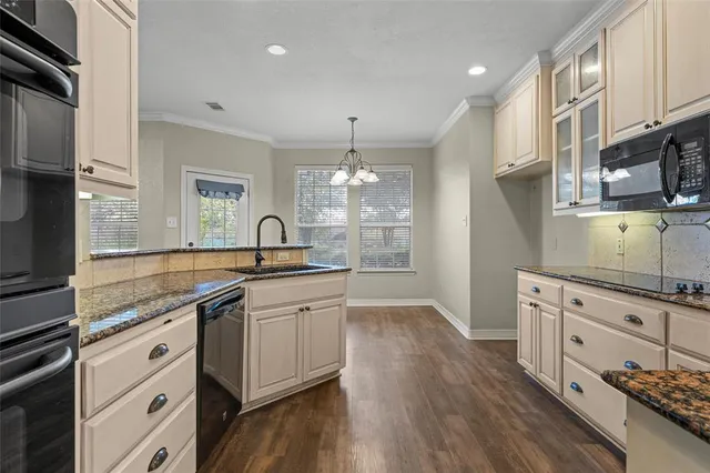 a kitchen with stainless steel appliances granite countertop a sink dishwasher a stove and white cabinets with wooden floor