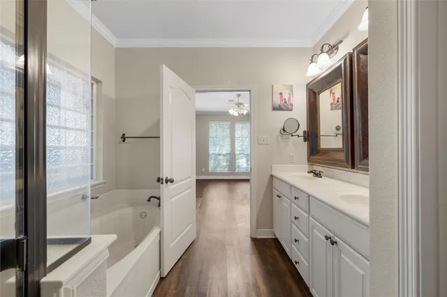 a bathroom with a double vanity sink and mirror with wooden floor