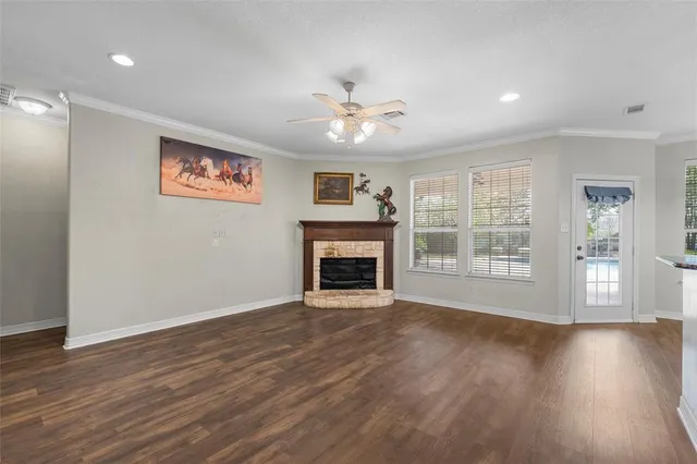 a view of an empty room with wooden floor fireplace and a window