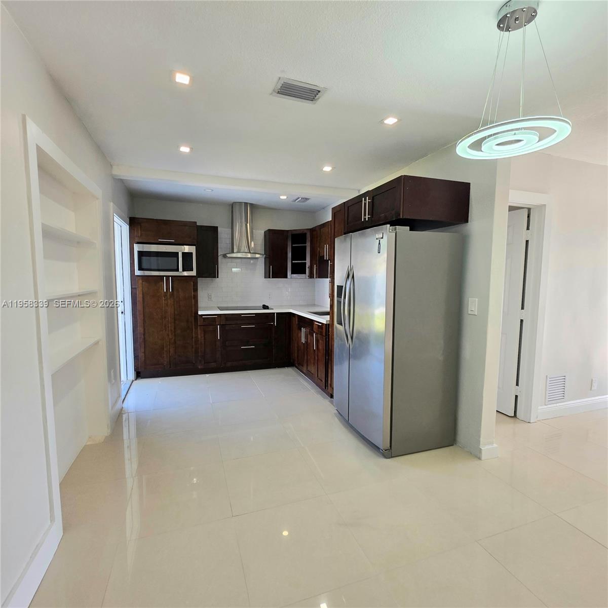 7555 Southwest 28th Street Road Miami, FL 33155 - Photo 3 of 11 a large kitchen with stainless steel appliances kitchen island a refrigerator and a stove top oven