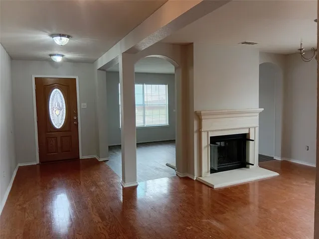 an empty room with wooden floor a fireplace and windows
