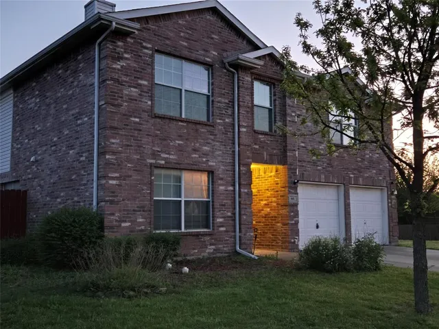 a brick building with a small yard and a large tree