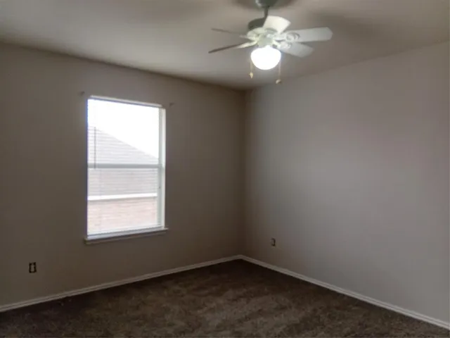 an empty room with a window and a fan