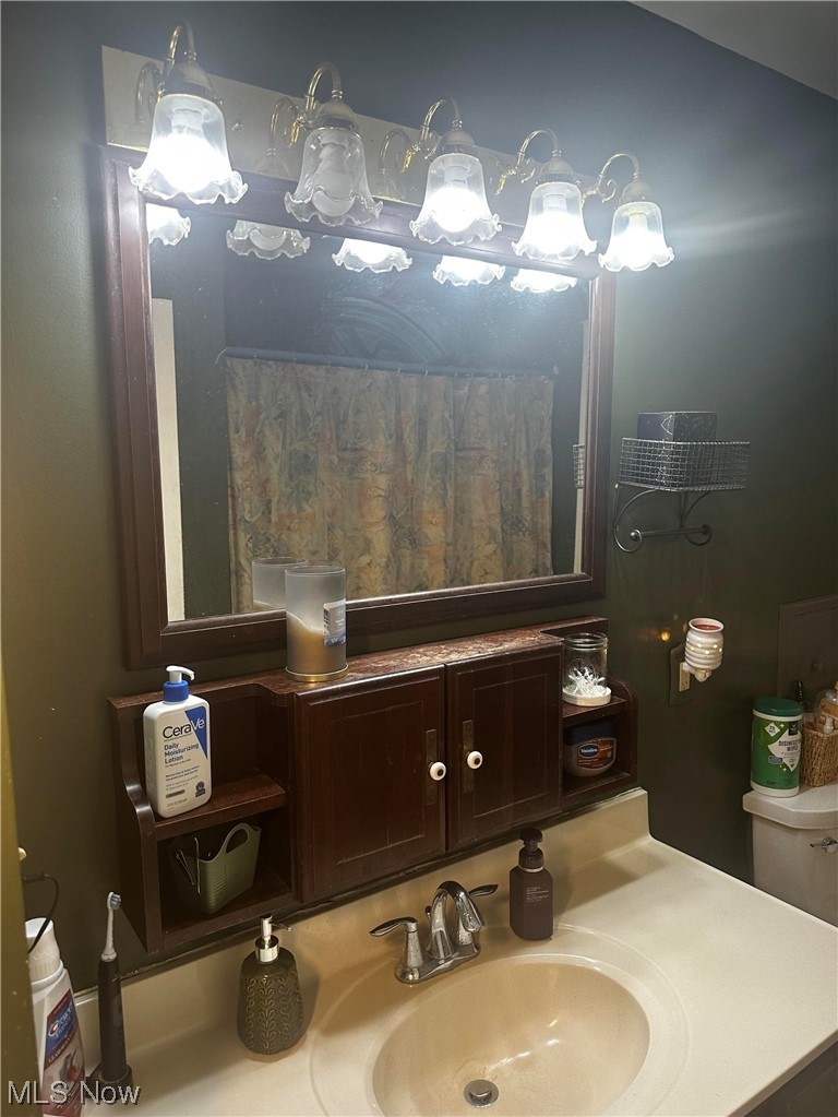 2444 Manchester Road Akron, OH 44314 - Photo 13 of 26 Bathroom featuring toilet, an inviting chandelier, and sink