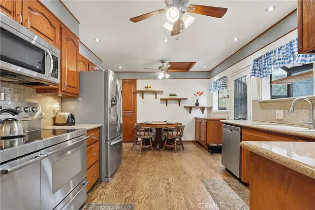 a kitchen with stainless steel appliances granite countertop a sink dishwasher stove refrigerator and cabinets with wooden floor