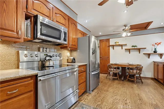 a kitchen with stainless steel appliances granite countertop a refrigerator a stove top oven a sink dishwasher and white cabinets with wooden floor
