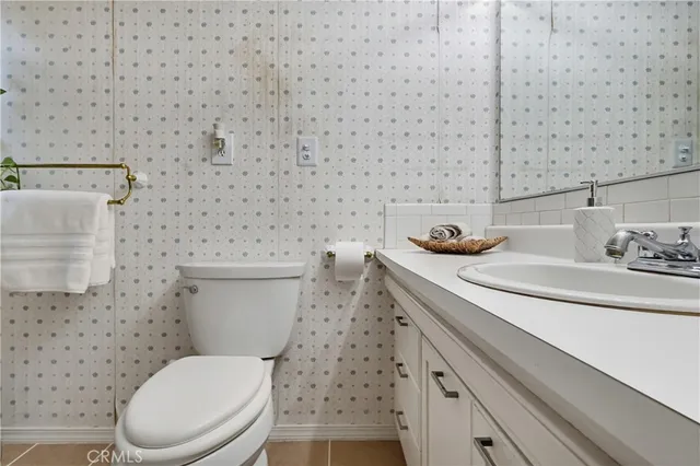 a bathroom with a granite countertop toilet a sink and a mirror