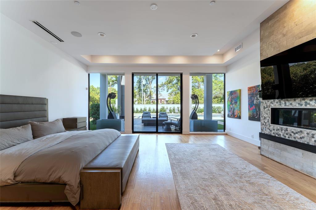 5959 Colhurst Street Dallas, TX 75230 - Photo 22 of 35 a spacious bedroom with a balcony a bed and a fireplace