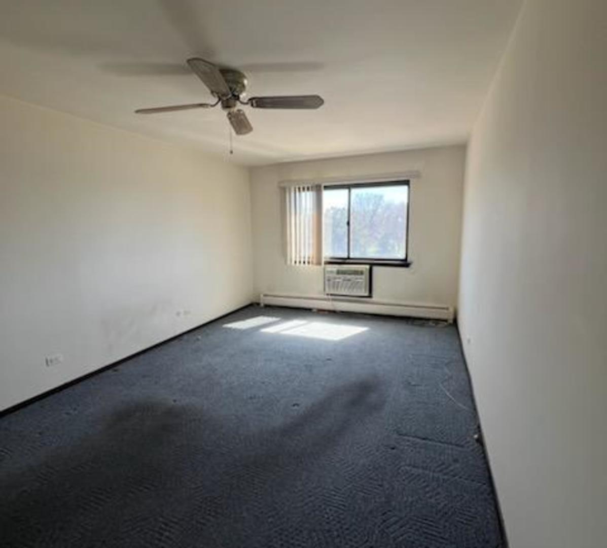 239 North Mill Road, Unit 405A Addison, IL 60101 - Photo 9 of 14 an empty room with a ceiling fan and windows