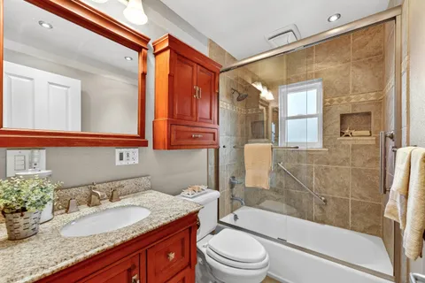 a bathroom with a granite countertop sink toilet and shower