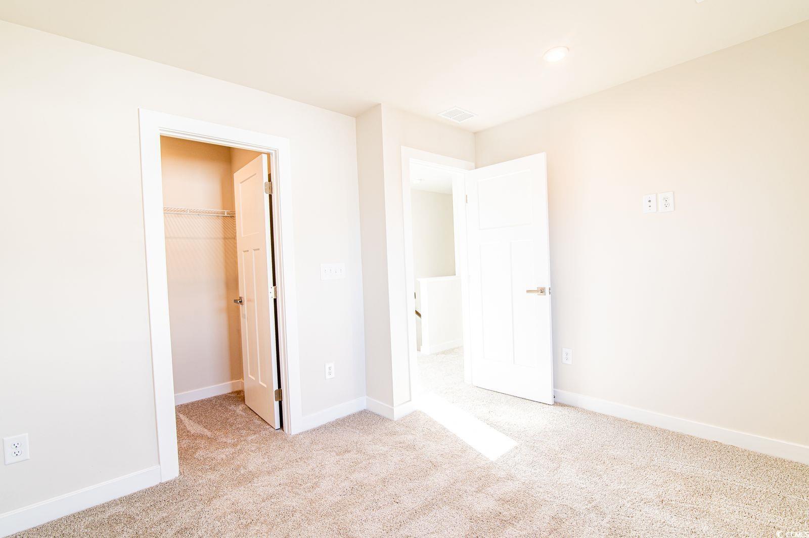 2812 Rowyn Street Longs, SC 29568 - Photo 16 of 27 Unfurnished bedroom featuring a walk in closet and light colored carpet