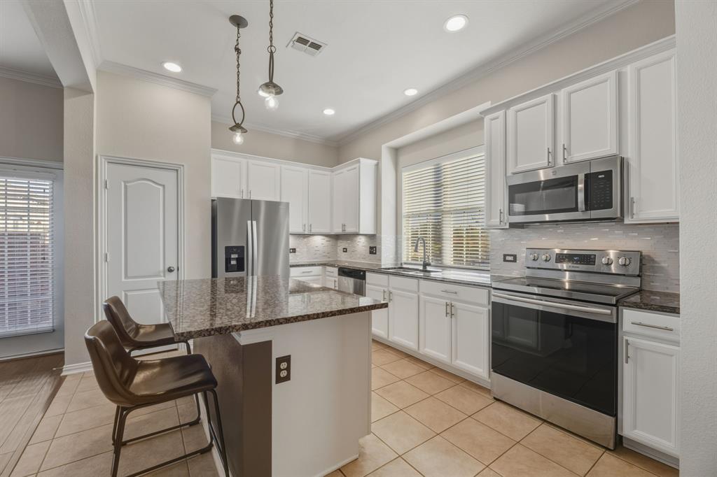 4027 Rome Court Irving, TX 75038 - Photo 12 of 33 a kitchen with stainless steel appliances granite countertop a stove top oven a sink dishwasher a refrigerator and white cabinets with wooden floor