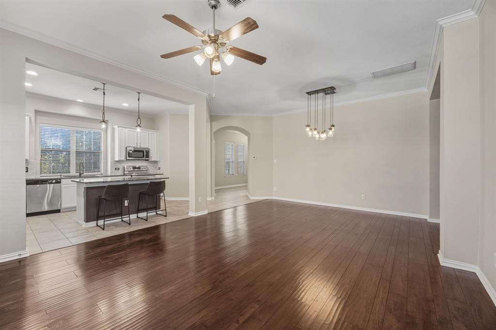 4027 Rome Court Irving, TX 75038 - Photo 8 of 33 an empty room with wooden floor a kitchen view and a fireplace
