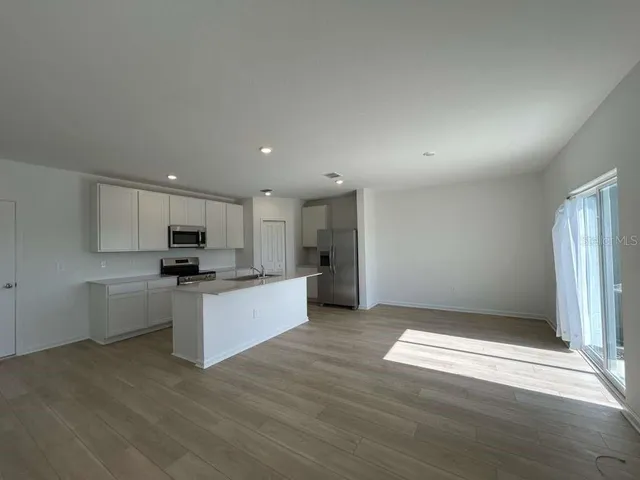a view of kitchen with refrigerator stove and wooden floor