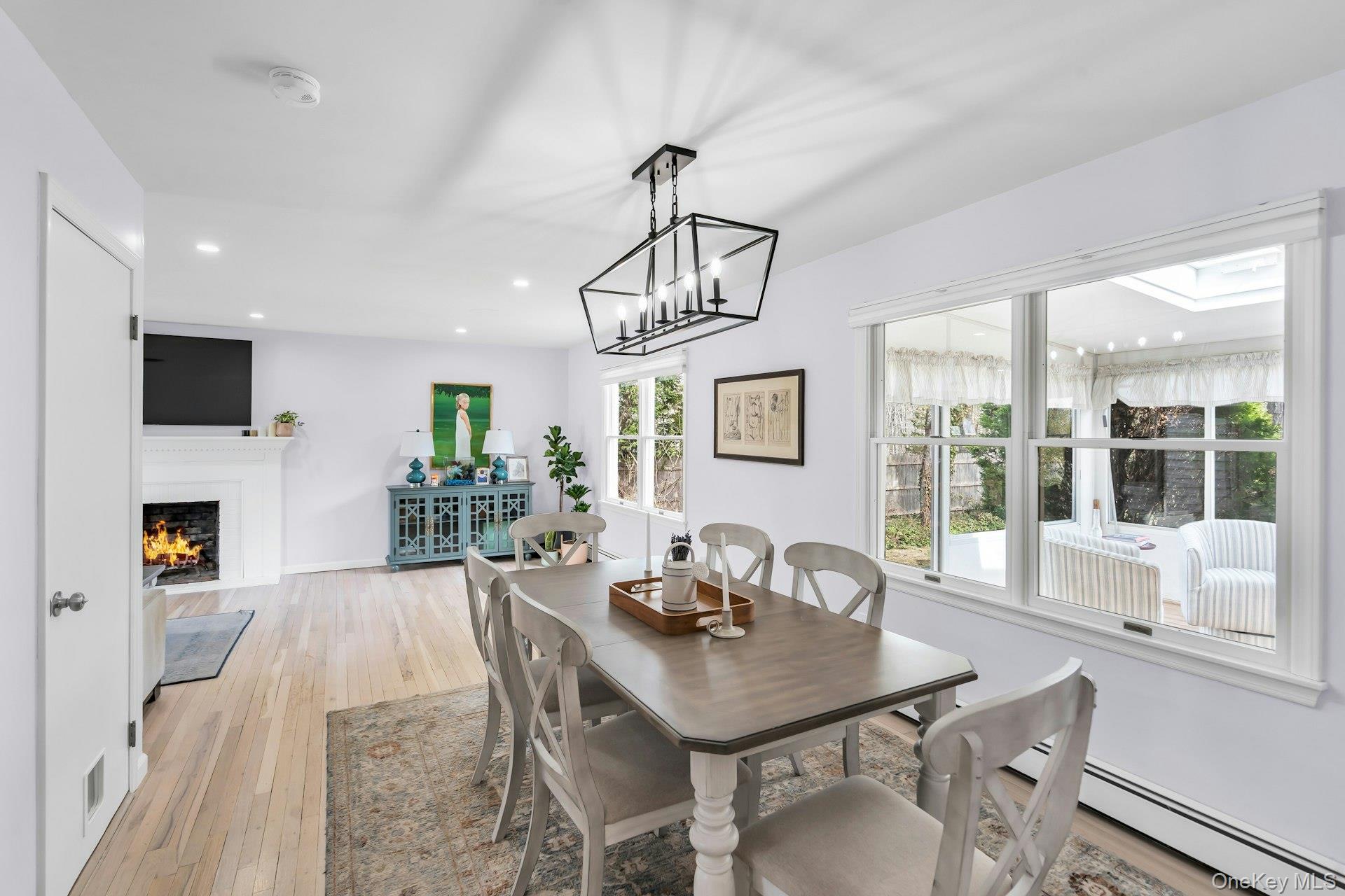 5845 North Bayview Road Southold, NY 11971 - Photo 6 of 26 Dining area with contemporary light fixture, large windows, hardwood flooring, and baseboard heating