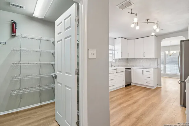 a view of a kitchen with white cabinets and wooden floor