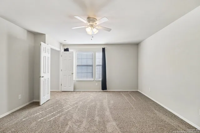 a view of an empty room with chandelier fan