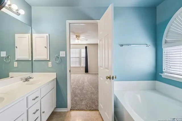 a bathroom with a tub a sink and mirror