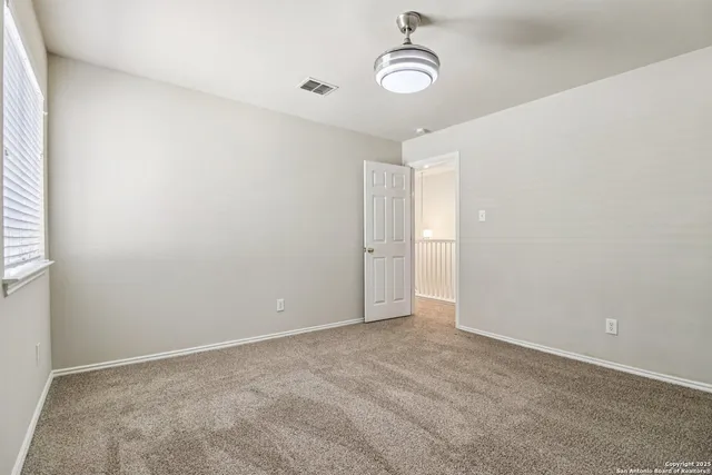 an empty room with windows and fan