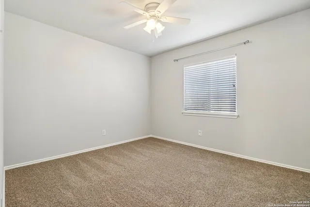 an empty room with a window and a ceiling fan