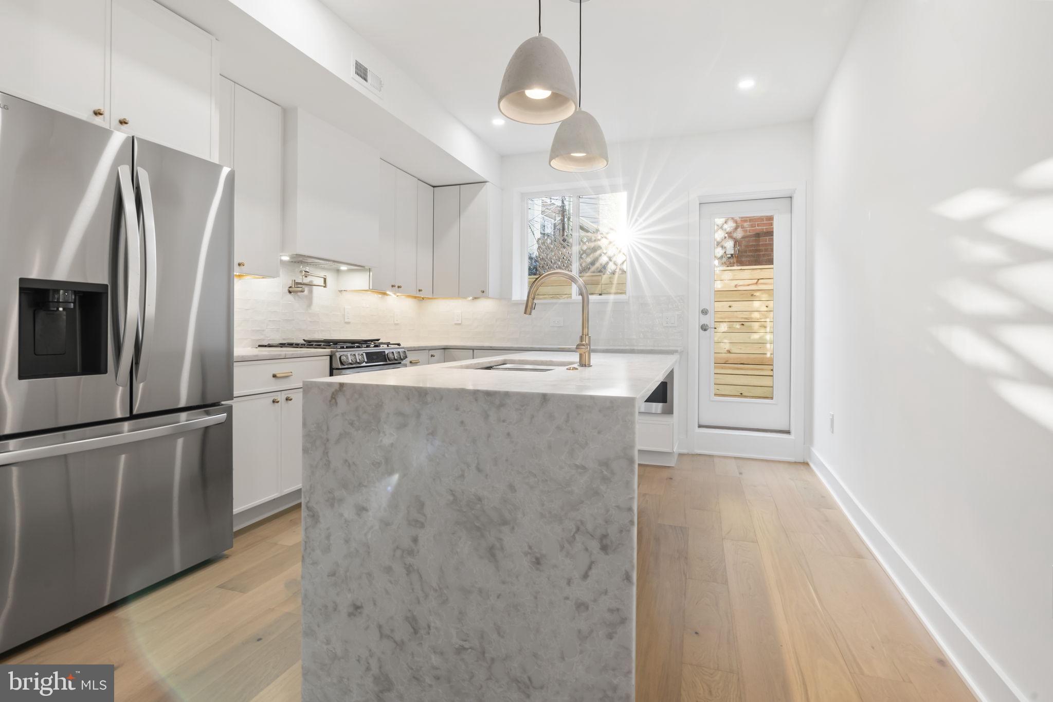 1318 South 8th Street Philadelphia, PA 19147 - Photo 12 of 47 a kitchen with stainless steel appliances granite countertop a refrigerator a sink a stove and a refrigerator with wooden floor