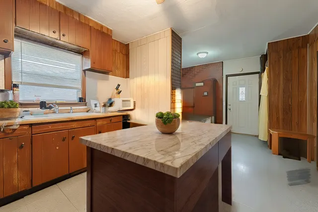 a kitchen with stainless steel appliances kitchen island granite countertop a sink a refrigerator and blue cabinets