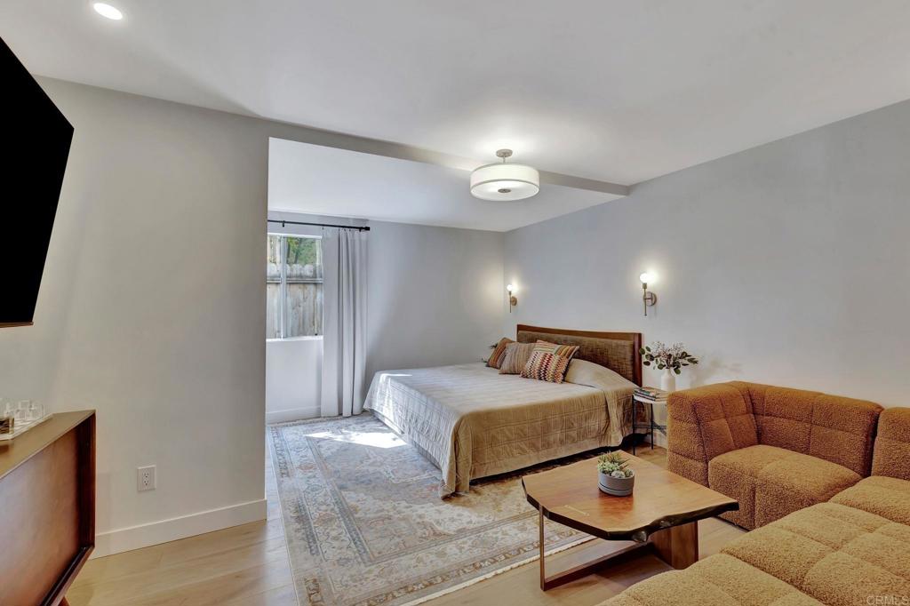 201 Sierra Ridge Drive Encinitas, CA 92024 - Photo 17 of 45 a spacious bedroom with a bed a couch and a flat screen tv