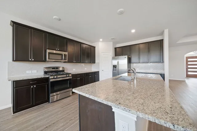 a kitchen with kitchen island granite countertop stainless steel appliances and wooden cabinets