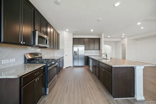 a large kitchen with stainless steel appliances double cabinets and a stove top oven