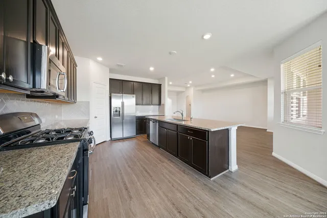 a kitchen with stainless steel appliances granite countertop wooden cabinets a stove top oven a sink and dishwasher