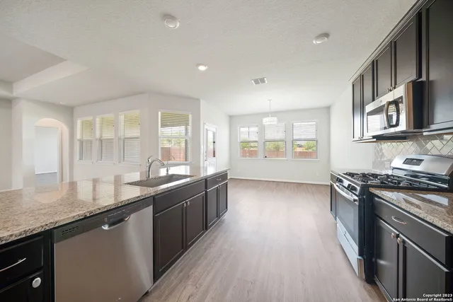 a large kitchen with granite countertop a stove top oven a sink a counter space and windows