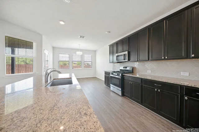 a kitchen with granite countertop wooden cabinets a stove top oven and granite counter top