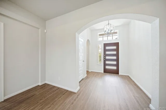an empty room with wooden floor staircase and a hallway