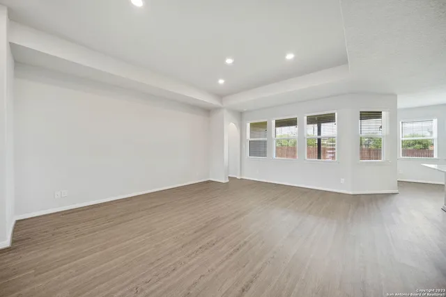 a view of an empty room with wooden floor and windows