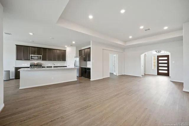 a view of kitchen with kitchen island a sink wooden floor and stainless steel appliances