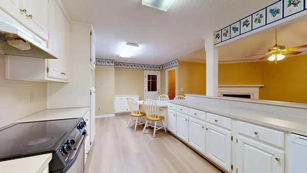 a kitchen with stainless steel appliances granite countertop a refrigerator a sink a stove and white cabinets with wooden floor