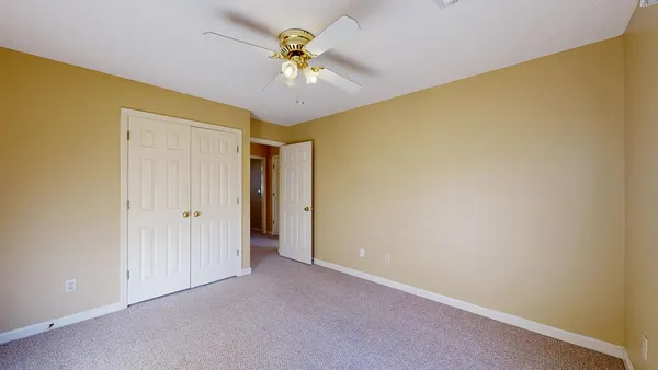 an empty room with a chandelier fan and windows