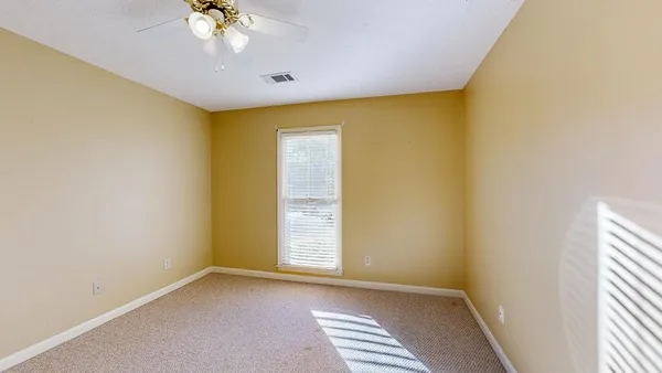 an empty room and chandelier fan